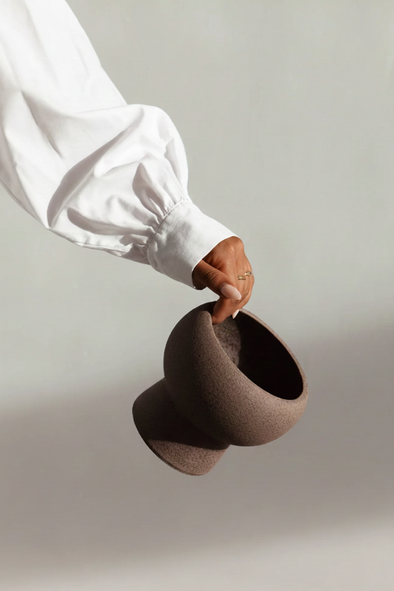 Person holding a brown felted woolen bowl against a plain background