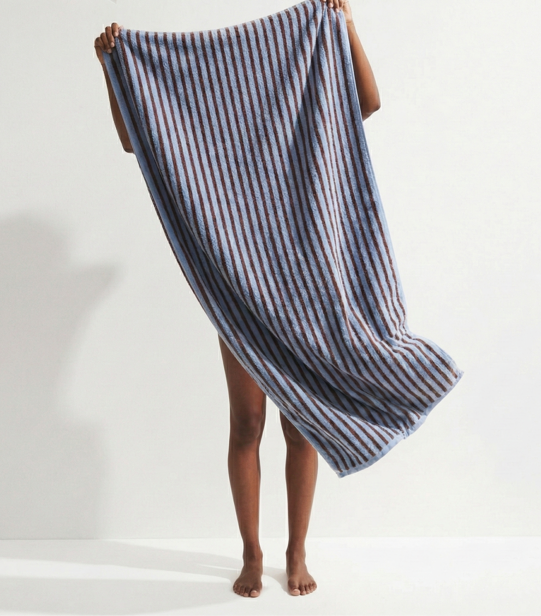 Person holding a blue and white striped towel against a white background