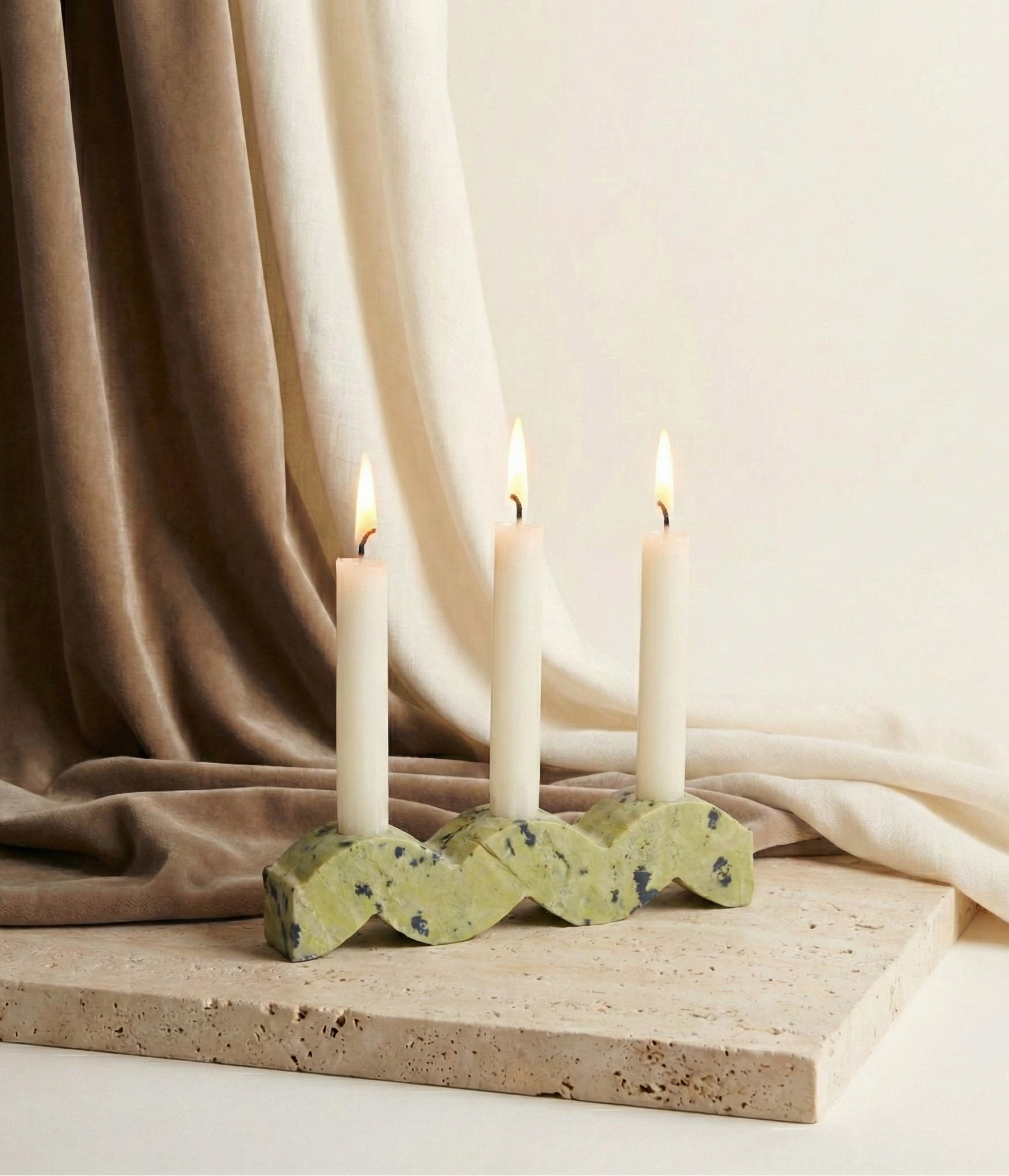 Decorative candle holder with three lit candles on a neutral background