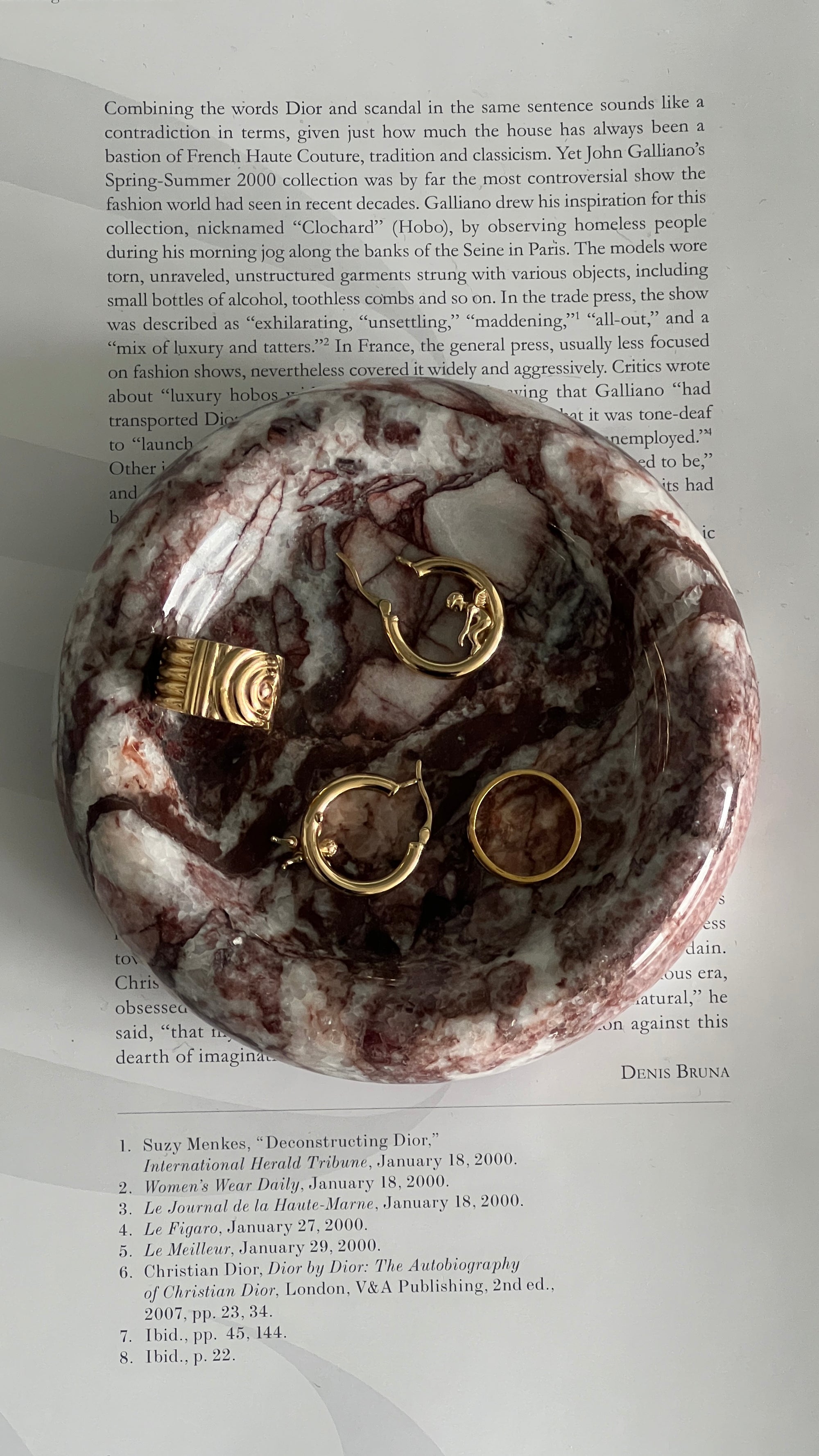 Marble-patterned dish with gold jewelry on a book page