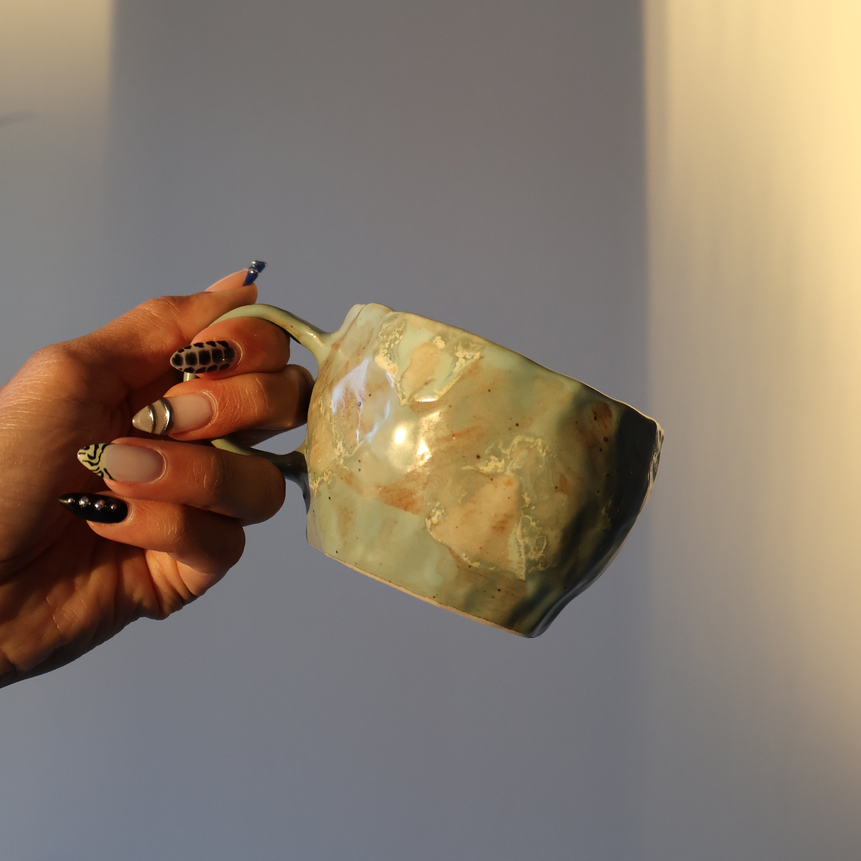 Hand holding a ceramic mug against a plain background