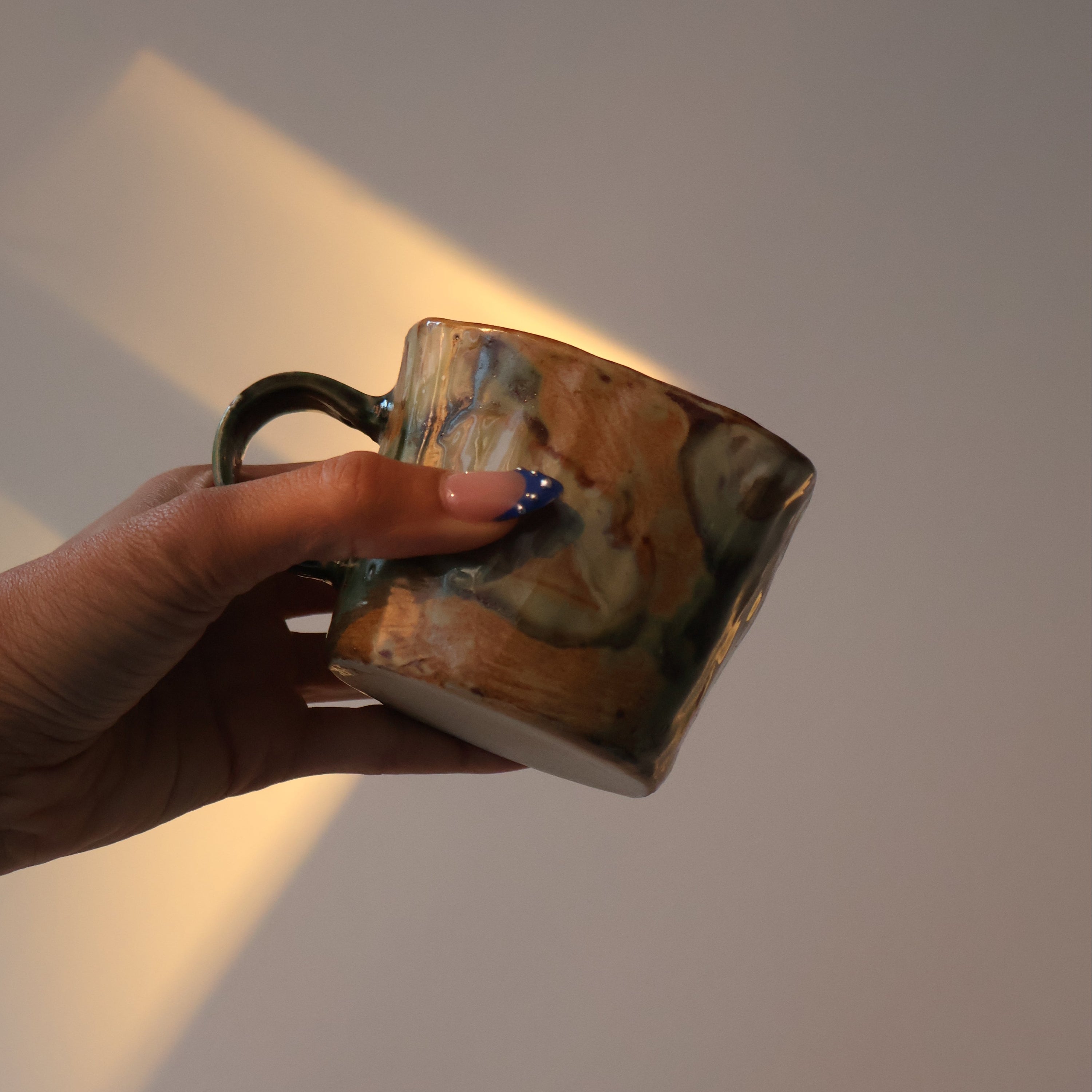 Hand holding a small ceramic cup against a plain background