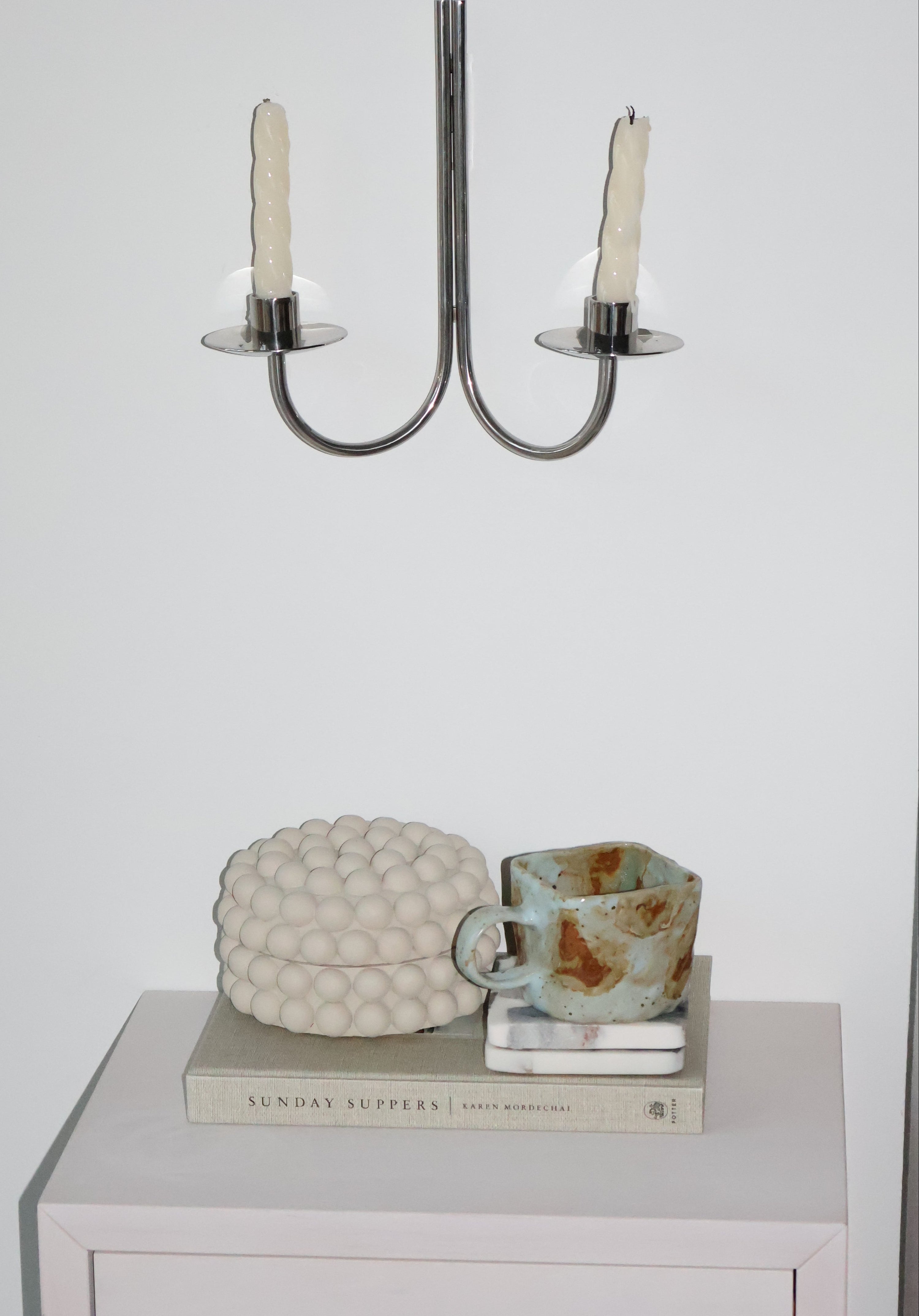 Decorative wall sconces and a textured wall art piece on a white wall.