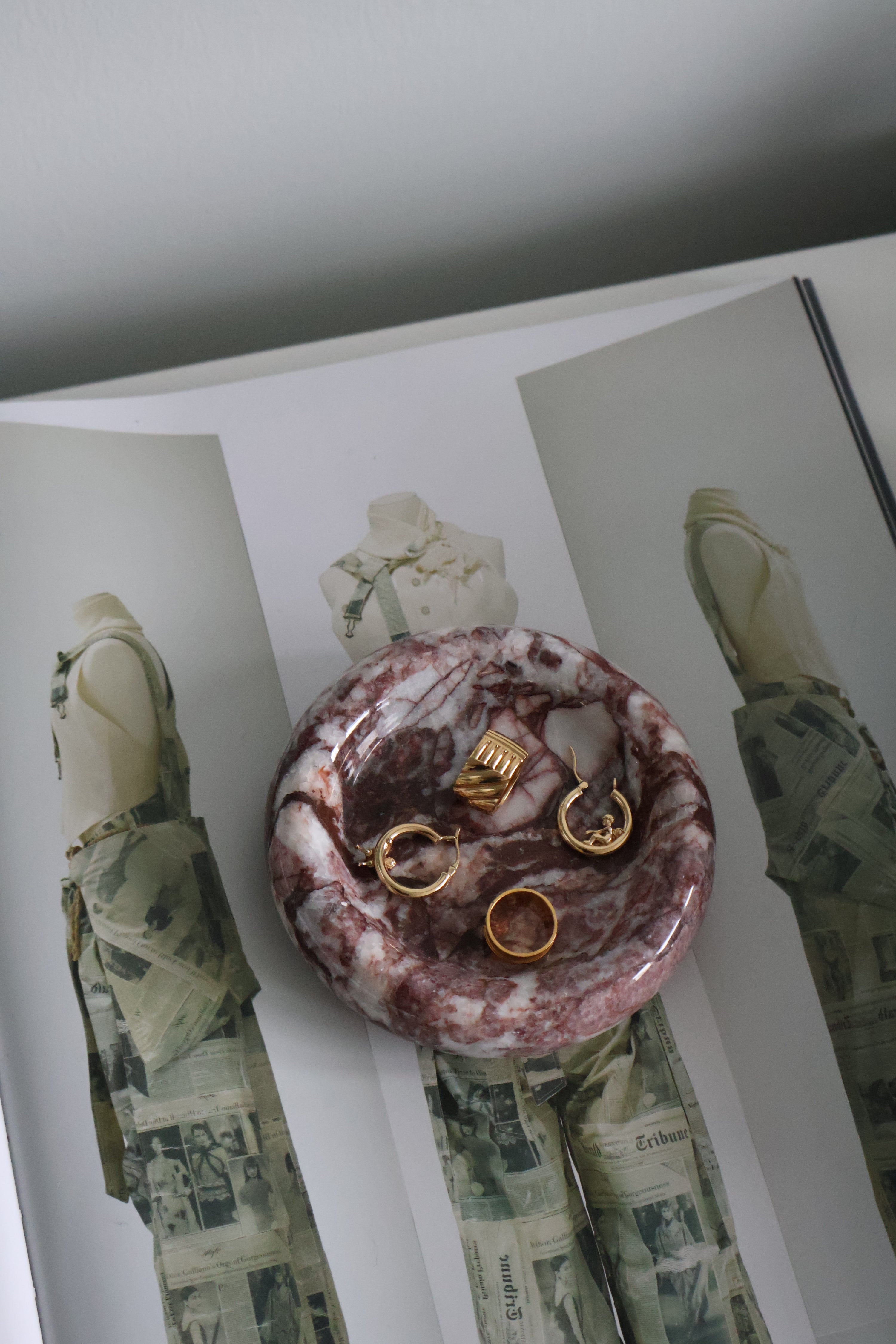 Marble-patterned jewelry dish with gold rings on a magazine background