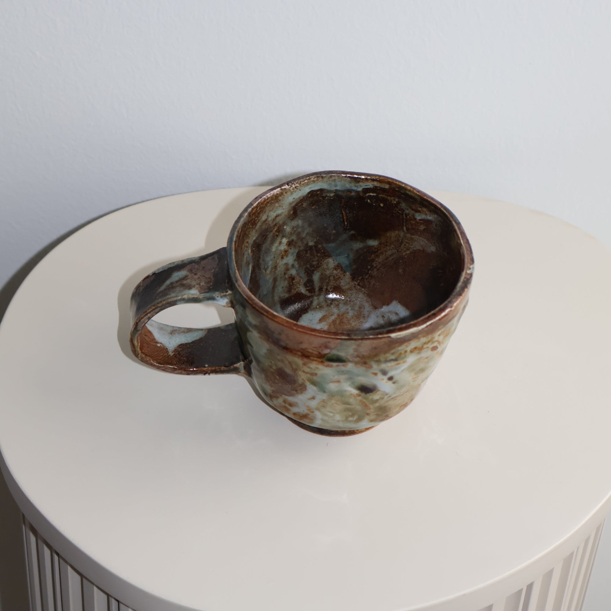 Ceramic cup with a textured surface on a white pedestal
