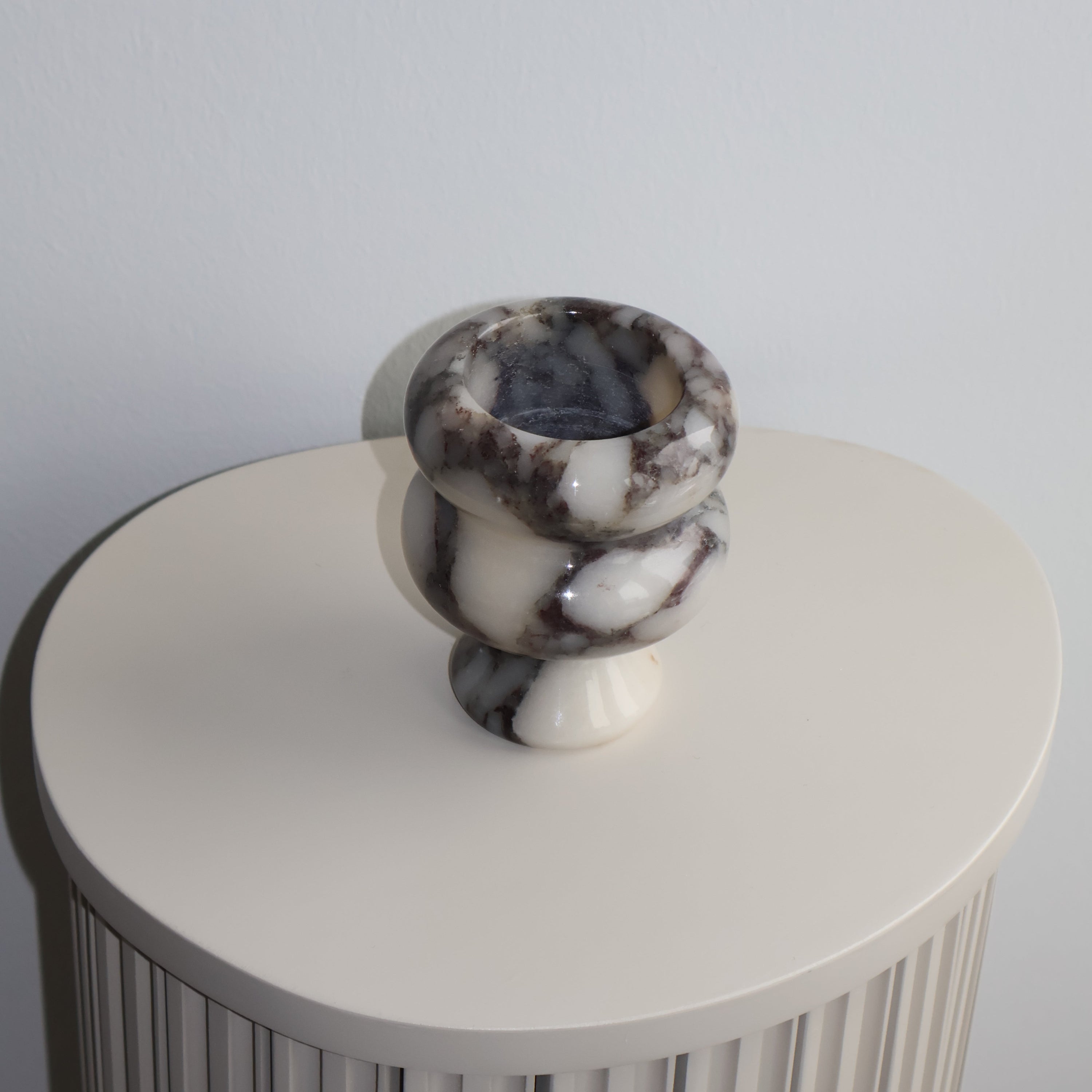 Decorative column with marble-like top on a plain background