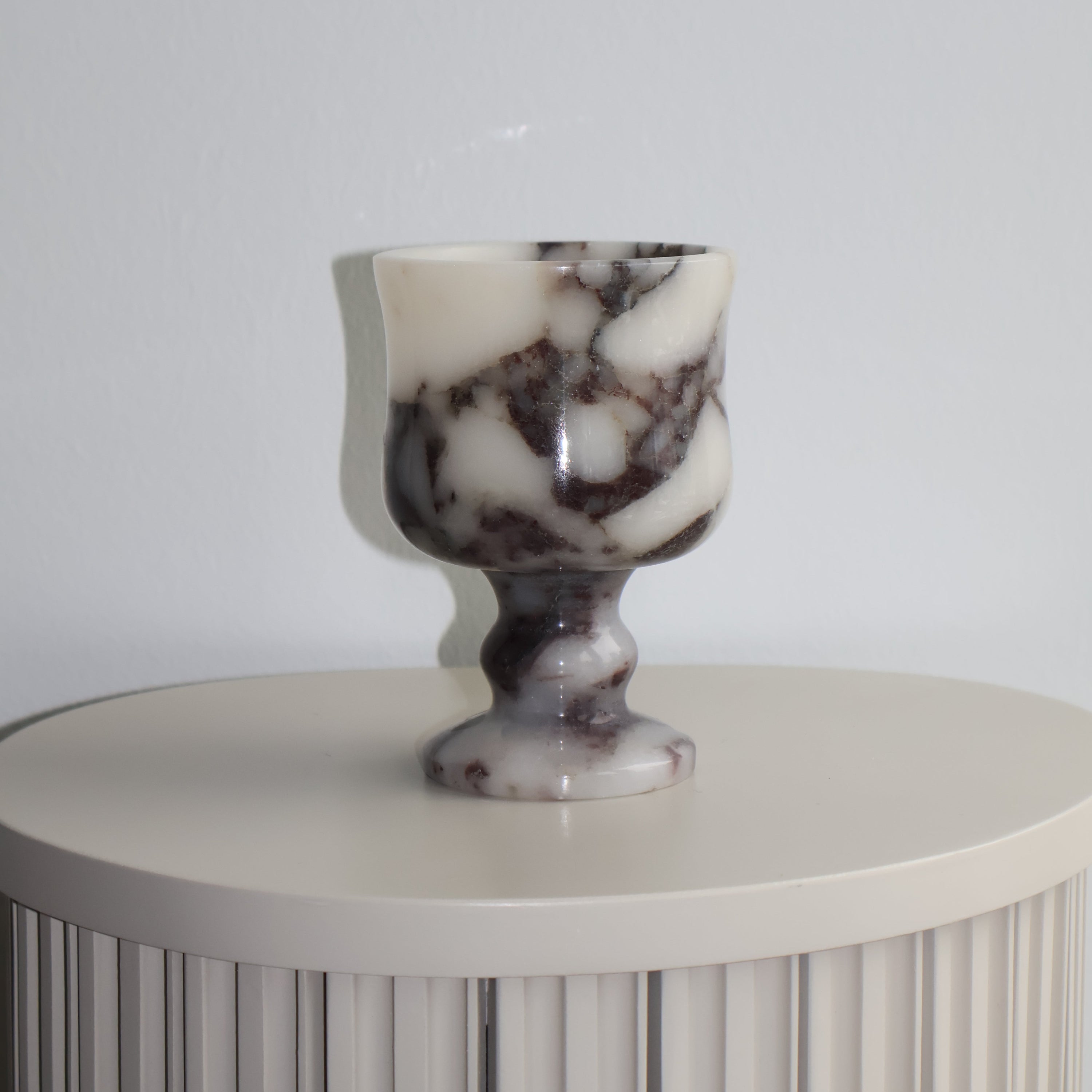 Decorative tea light holder with marble-like finial on a plain background