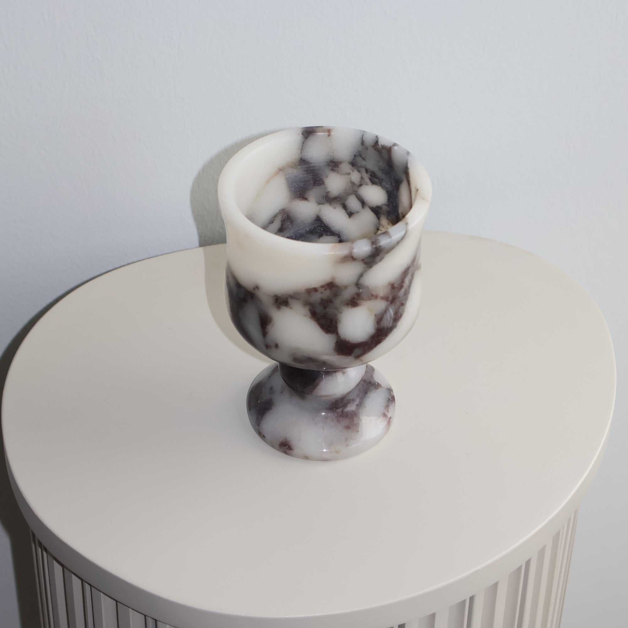 Decorative tea light holder with marble-textured top on a plain background