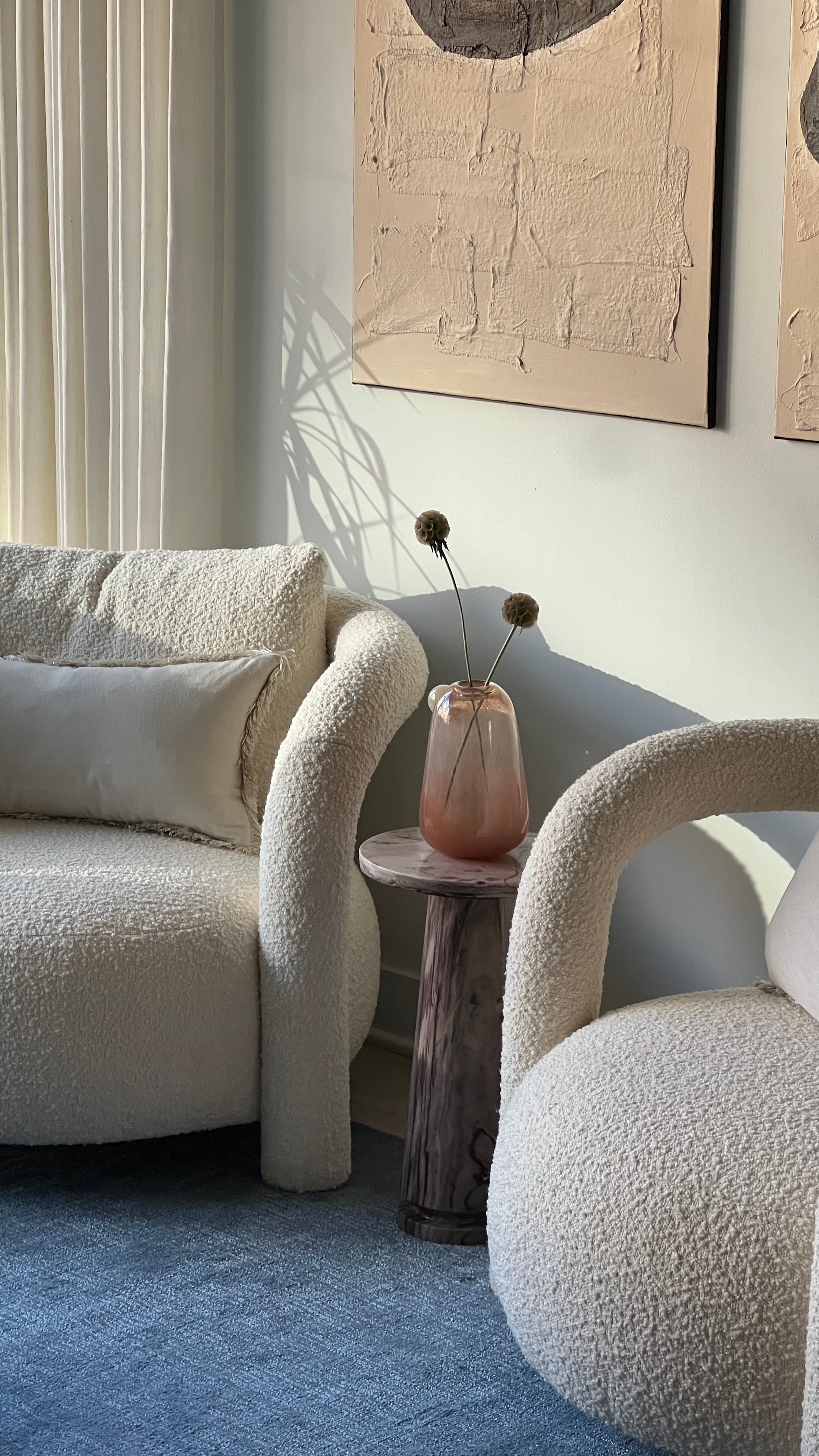 Modern living room with textured beige sofa, abstract art, and wooden side table.