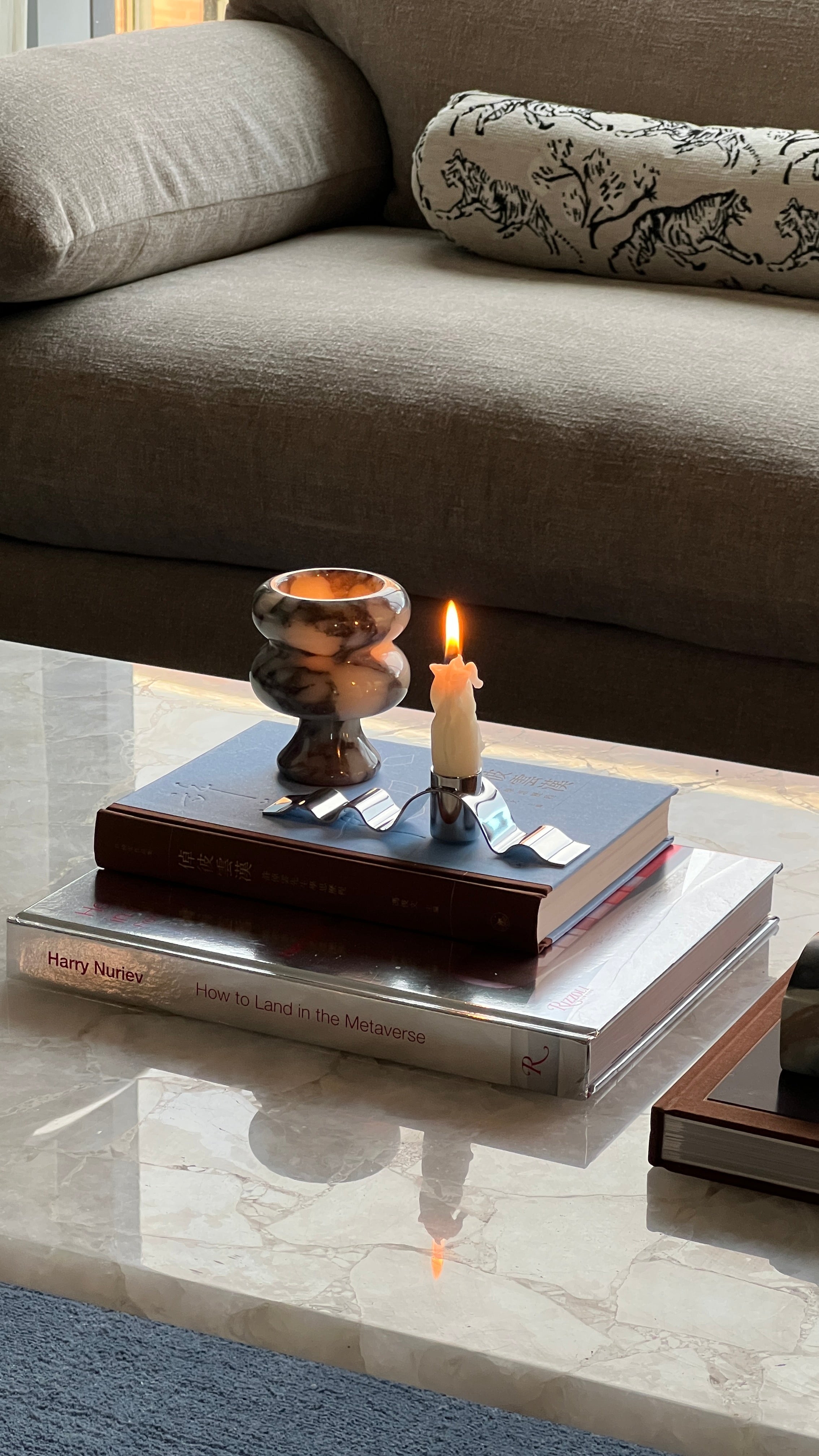 Candle on a stack of books with decorative items on a marble coffee table