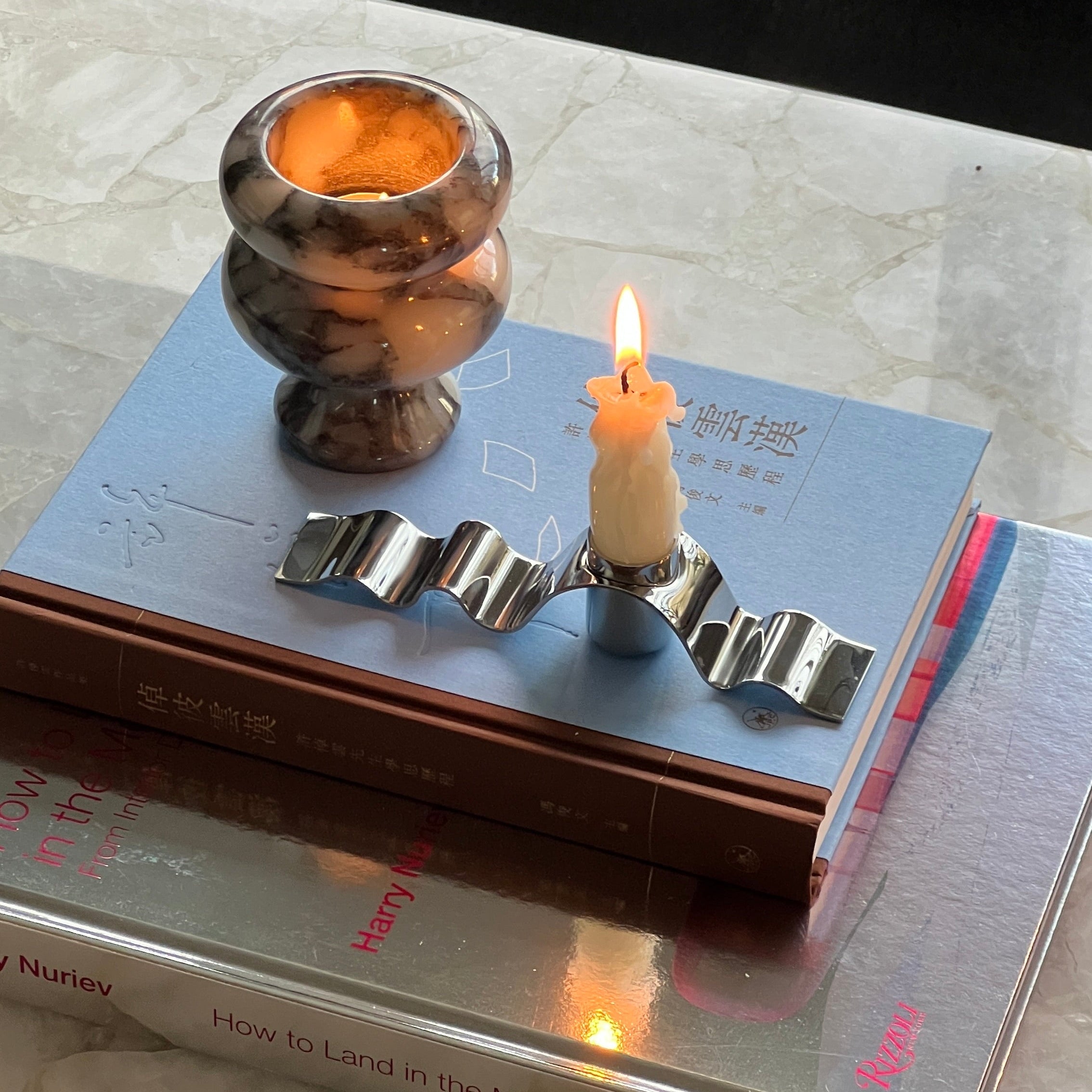 Candle in a holder on top of books with a blurred background
