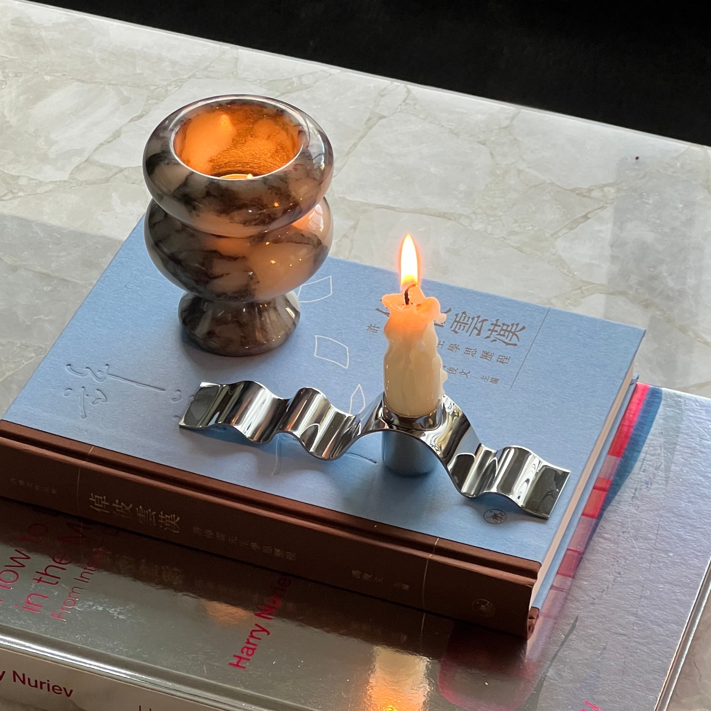 Candle in a holder on top of books with a blurred background