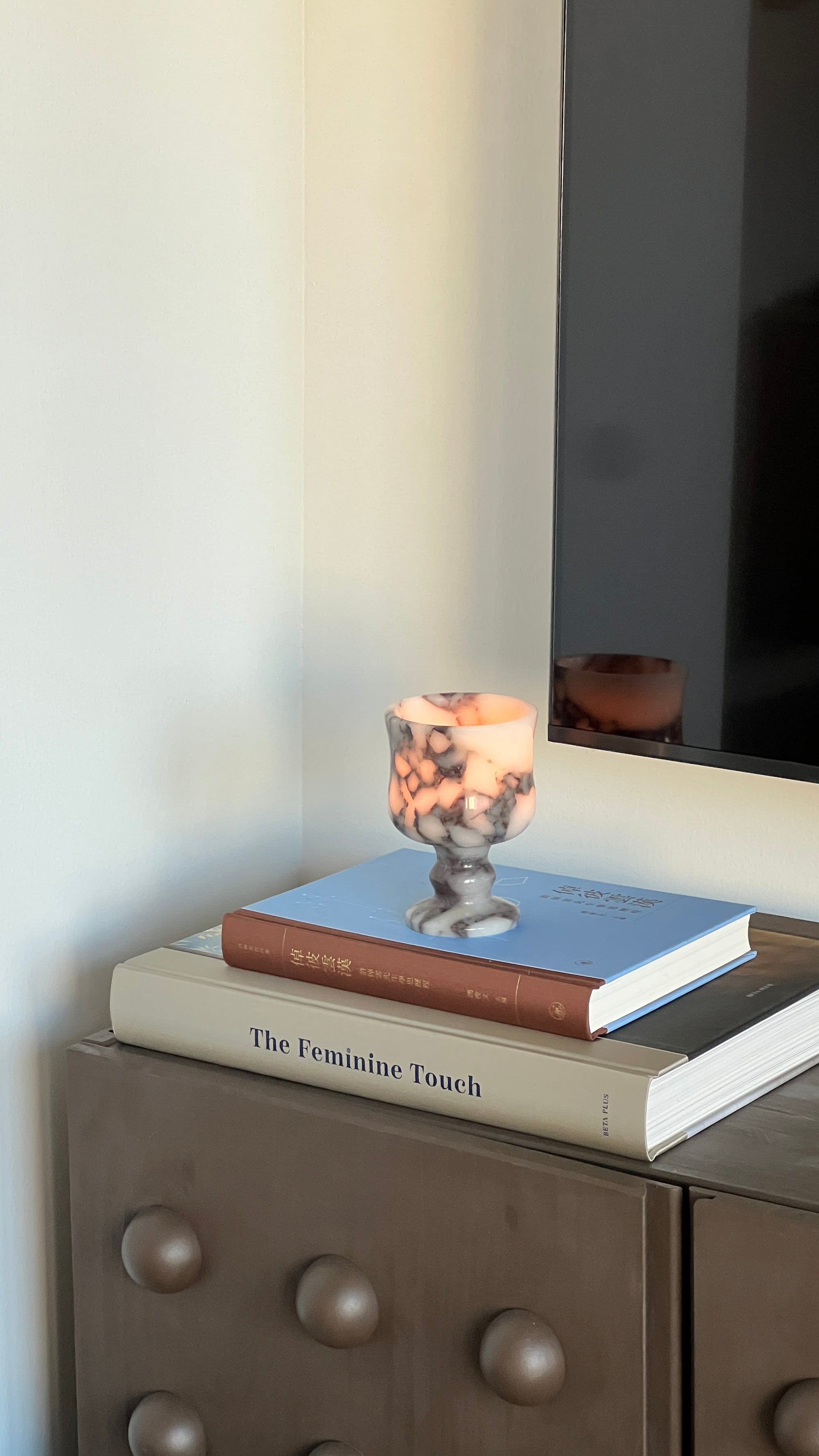 Candle in a holder on top of books with a blurred background