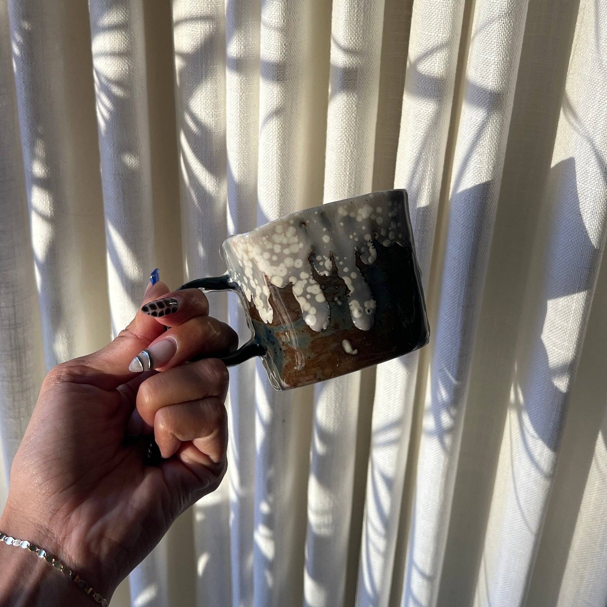Hand holding a paintbrush against a white curtain