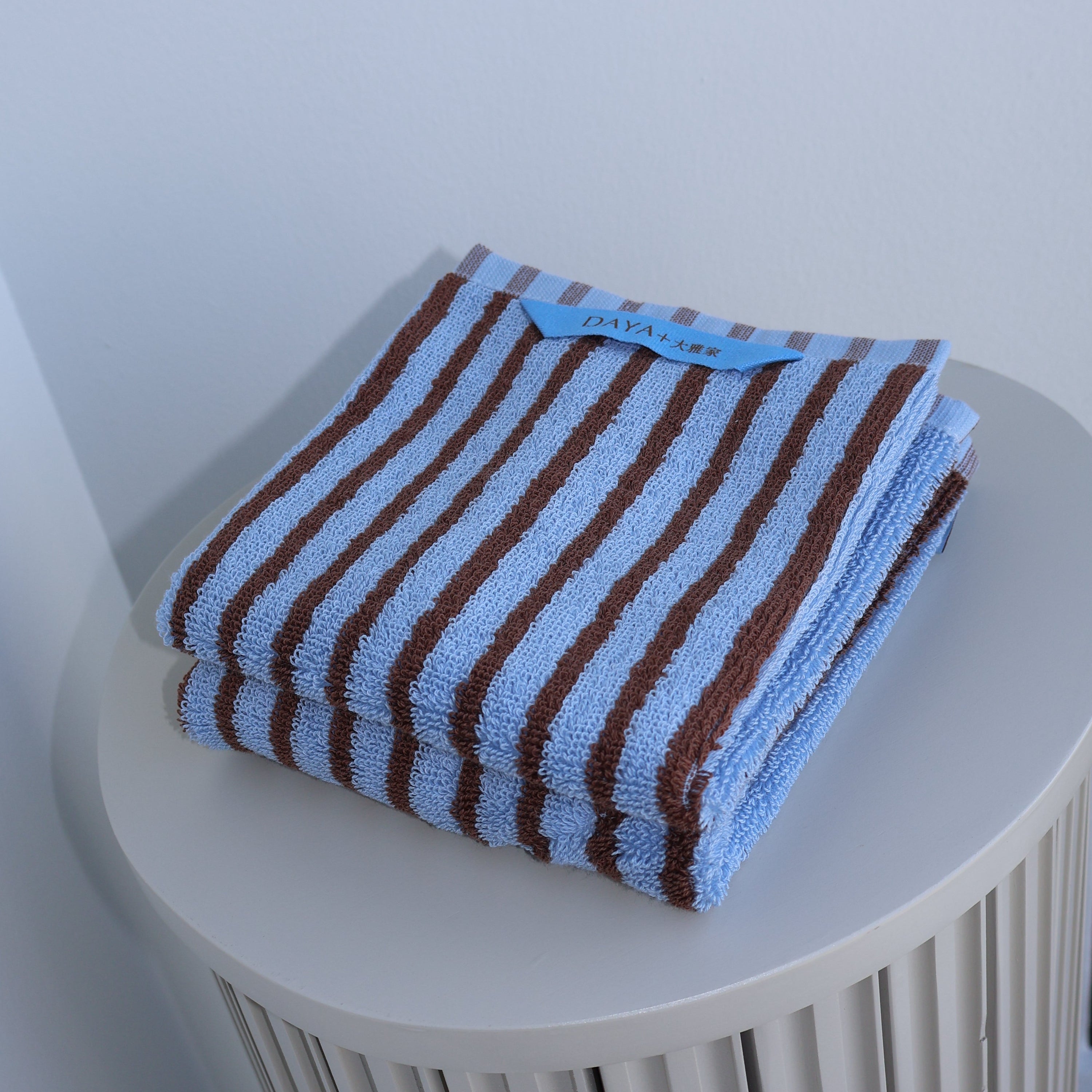 Striped towel on a white cylindrical holder against a light background